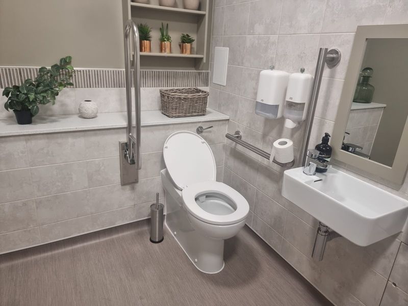 Fully fitted DDA-compliant disabled access bathroom with raised toilet, grab rails, accessible basin and care home interior styling — Smith EcoFlow complete accessibility bathroom installation